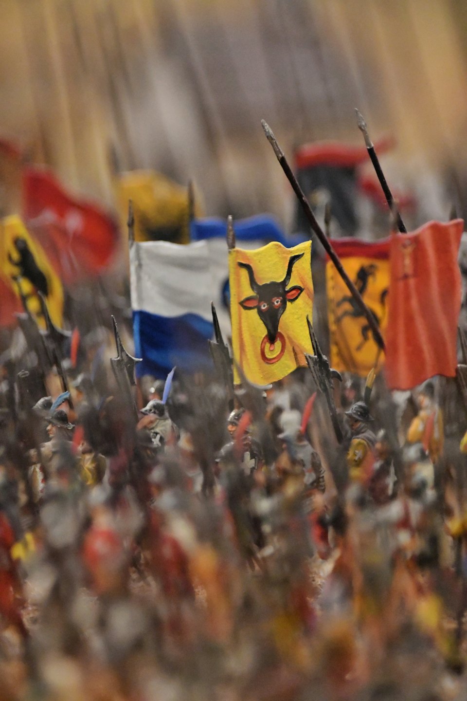 Miniature soldiers with a yellow bull flag stand in formation.