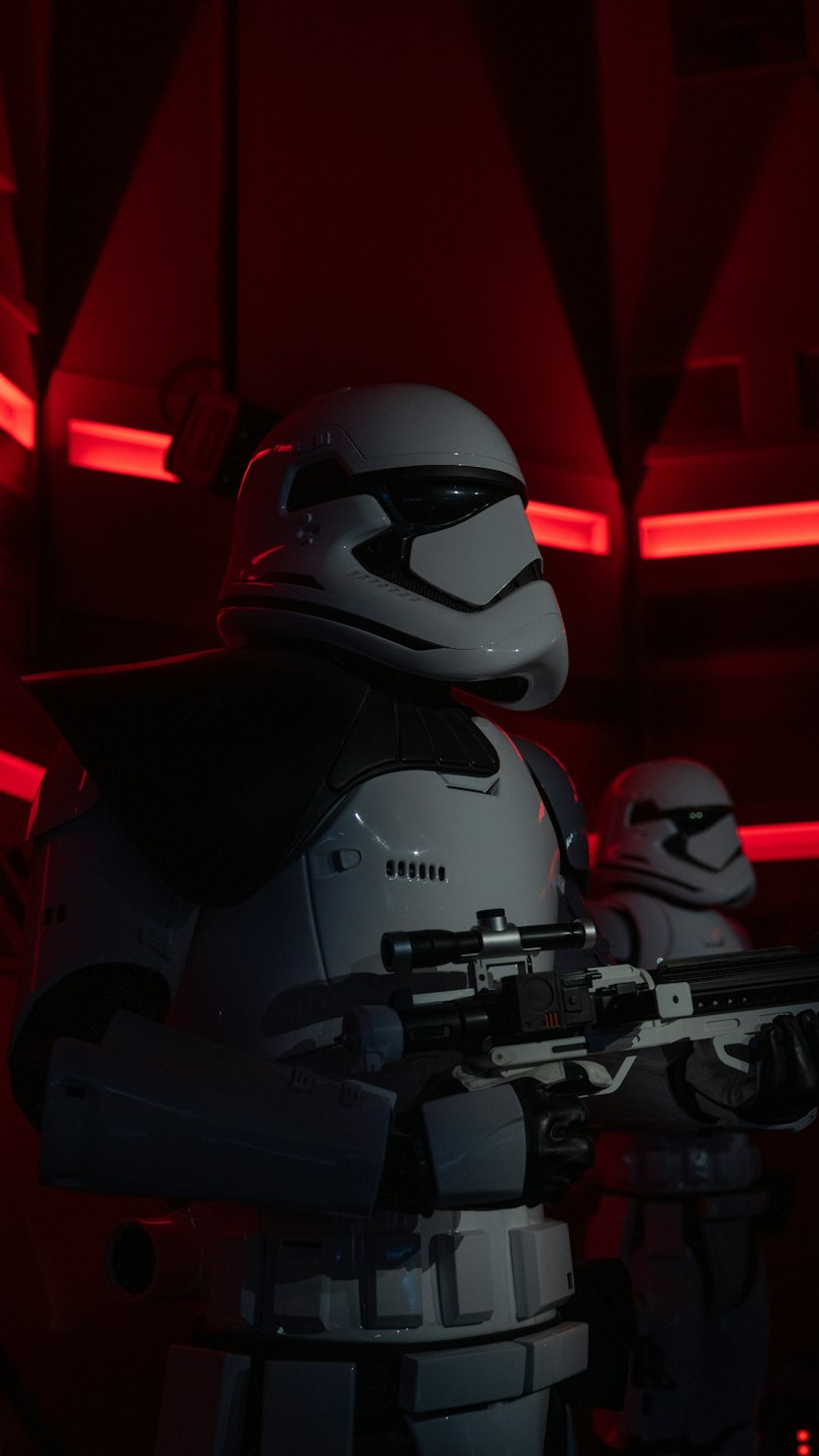 Two figures in futuristic armor holding rifles indoors.