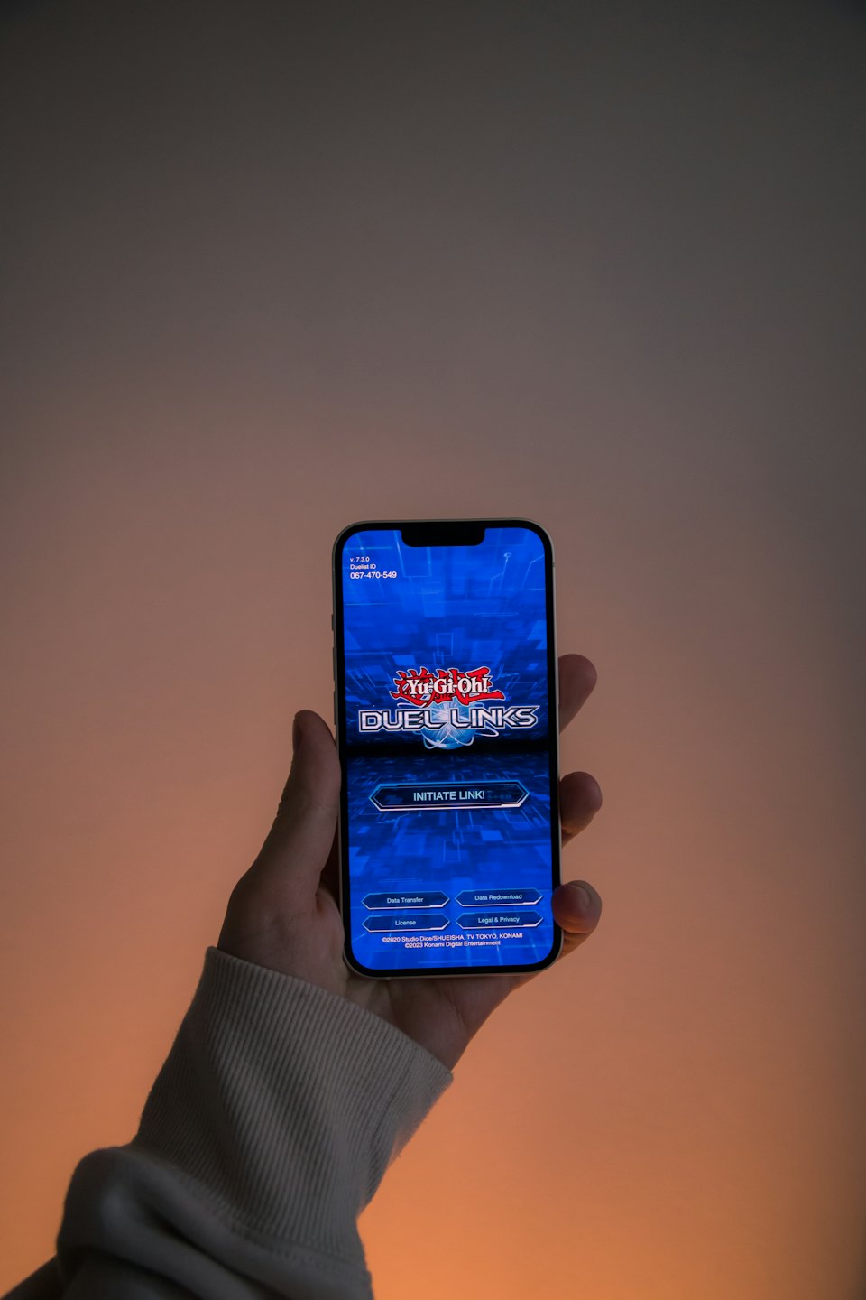Hand holds smartphone showing Yu-Gi-Oh Duel Links game.